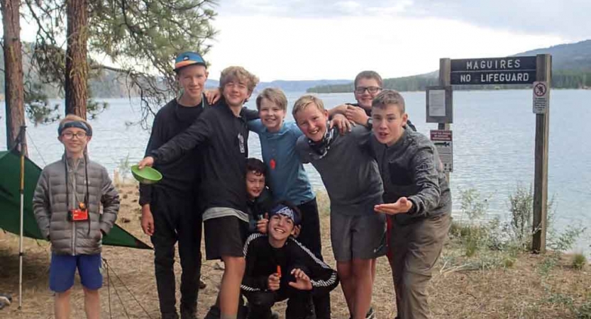 a group of boys smile at the camera beside a lake on an outward bound expedition in washington state